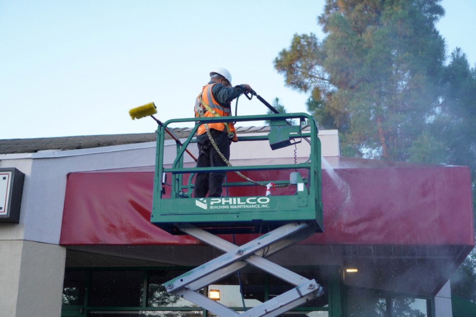 A Philco employee power washing a commercial clients awning at their store front