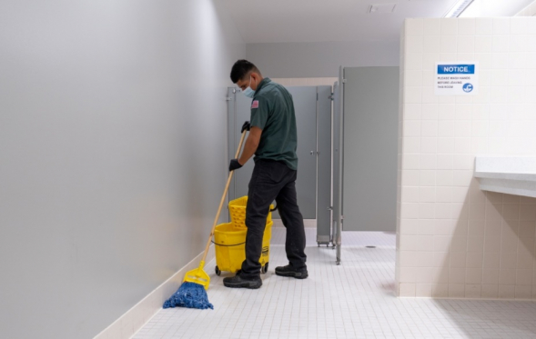 A Philco employee mopping the floor of a commercial clients bathroom