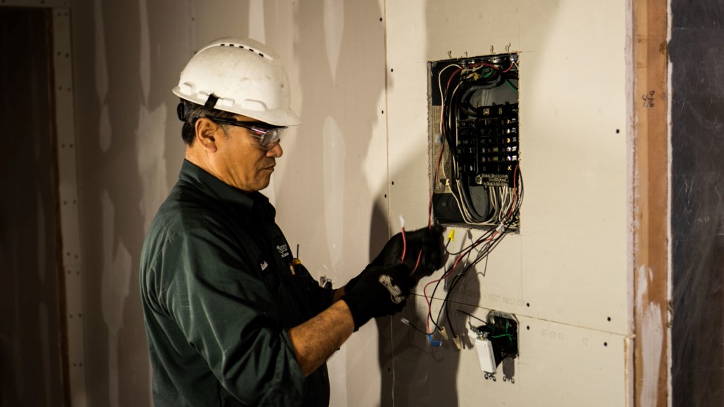 A Philco employee in a hard hat setting up the electrical system for a new construction client