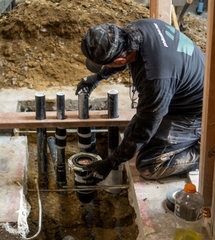 A Philco technician repairing plumbing pipes in a commercial clients office