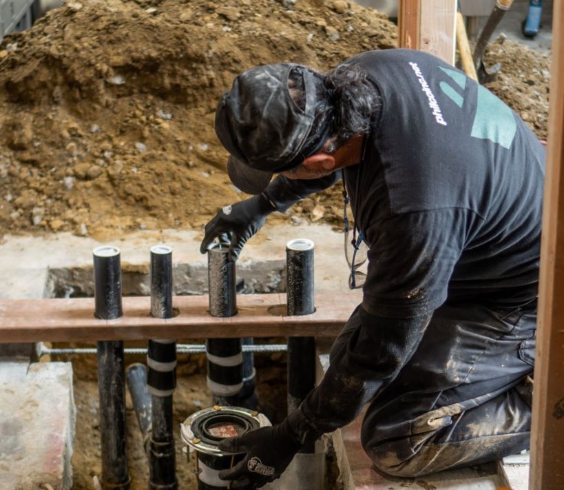 A Philco technician repairing plumbing pipes in a commercial clients office