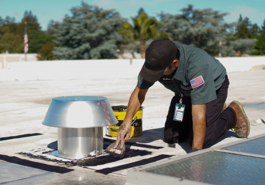 A Philco employee on a commercial clients roof sealing a metal vent